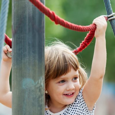 baby girl climbing at ropes on playground area